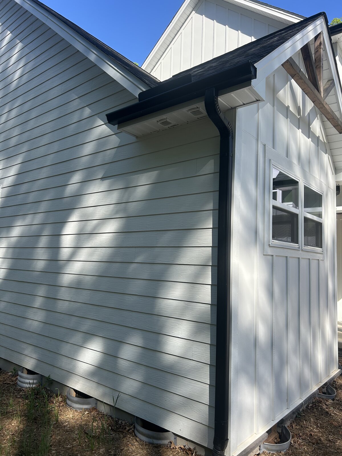 Black gutters on white board-and-batten home — Foothills Gutter Pro
